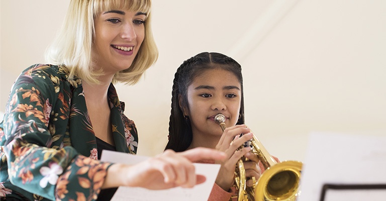 Woman teaching her student to play trumpet