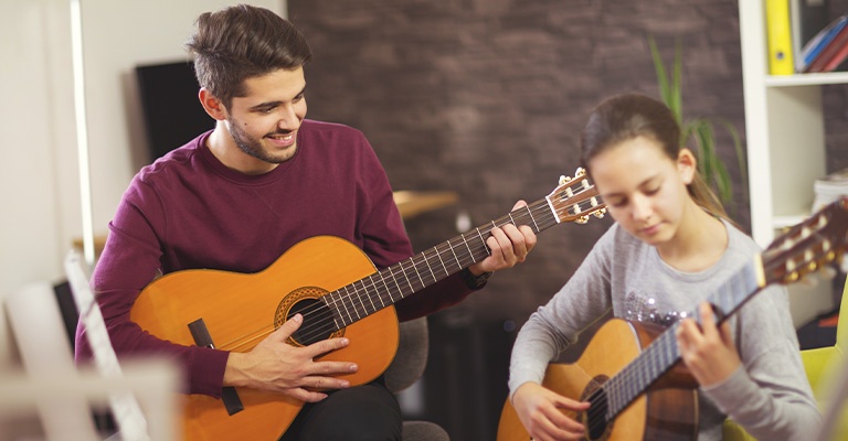 Instructor and student playing the guitar