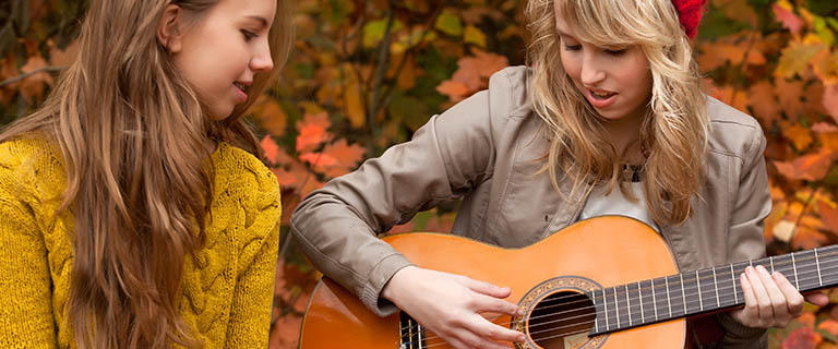 girl playing guitar and one girl listening