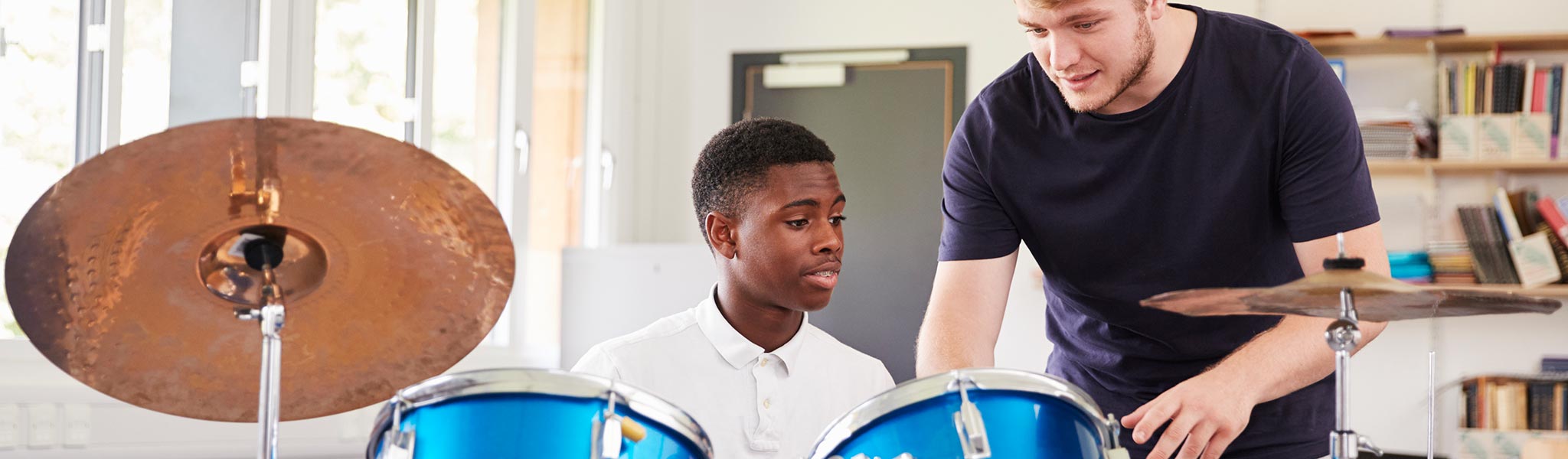 Male Pupil With Teacher Playing Drums In Music Lessonq
